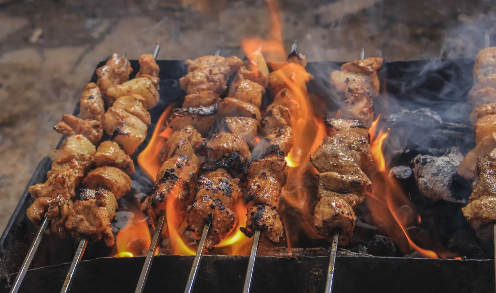 Skewers grilling over flaring charcoal